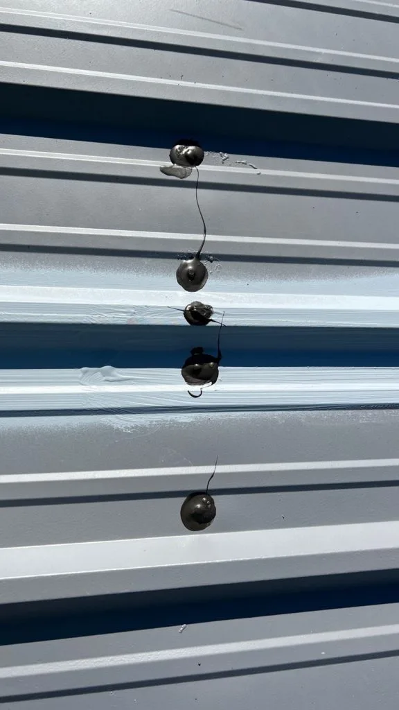 vertical line of bullet holes on metal siding